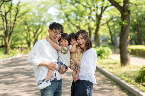 portrait of family under trees - asian ethnicity child four people couple imagens e fotografias de stock