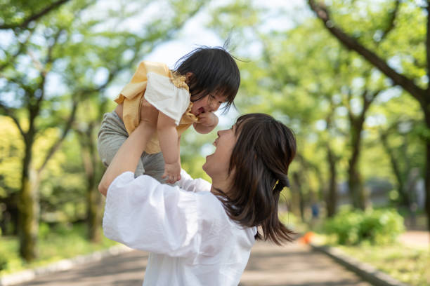 istock Mother lifting baby in park 1154757465