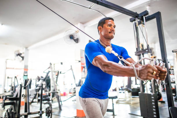 istock Asian man exercising at the gym with cables and pulleys 1154758007
