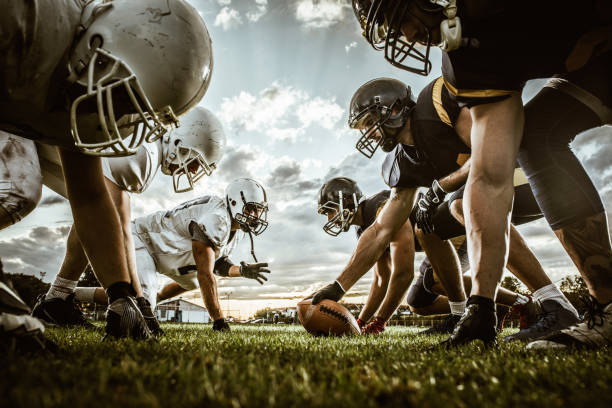 sotto la vista dei giocatori di football americano all'inizio della partita. - offensive line foto e immagini stock