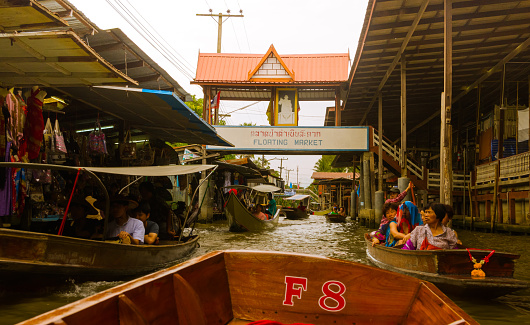 Bangkok, Thailand - August 21, 2017: unidentified tourists and traditional vendors on the famous floating market Damnoen Saduak in Bangkok. It is a traditional market on the khlongs, where they sell goods and food from the boats.