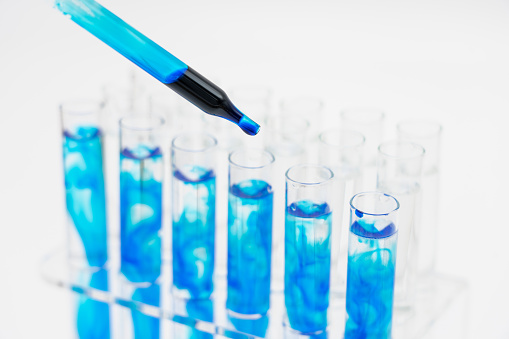 En el laboratorio, los científicos sintetizaron y analizaron el compuesto al dejar caer el líquido de color en los tubos de ensayo. Fondo blanco de cerca. photo