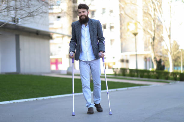 Young beautiful bearded man with walking sticks on the street, taking a stroll and enjoying sunny day. Outdoor environment