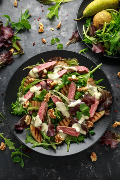Grilled Beef Steak salad with pears, walnuts and greens vegetables and blue cheese sauce. healthy food. Grilled Beef Steak salad with pears, walnuts and greens vegetables and blue cheese sauce. healthy food steak salad stock pictures, royalty-free photos & images