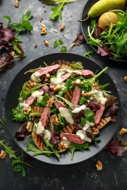Grilled Beef Steak salad with pears, walnuts and greens vegetables and blue cheese sauce. healthy food