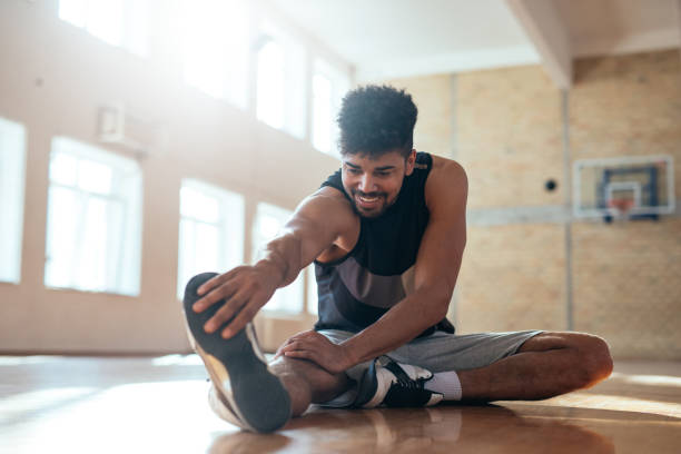 Stretch your limits! Photo of an african american basketball player doing some stretching exercises before practice. warm up exercise stock pictures, royalty-free photos & images