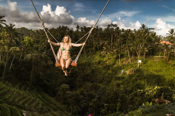 istock Happy woman having fun on a swing above the rainforest. 1154765879