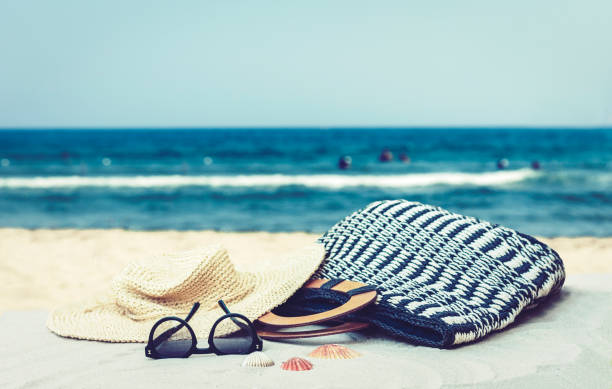 istock Straw hat, bag and sun glasses on a tropical beach 1154765999