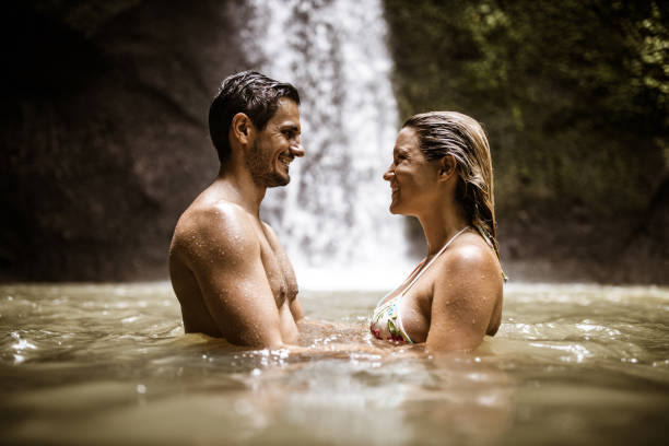 istock Young happy couple talking in water at rainforest. 1154766126
