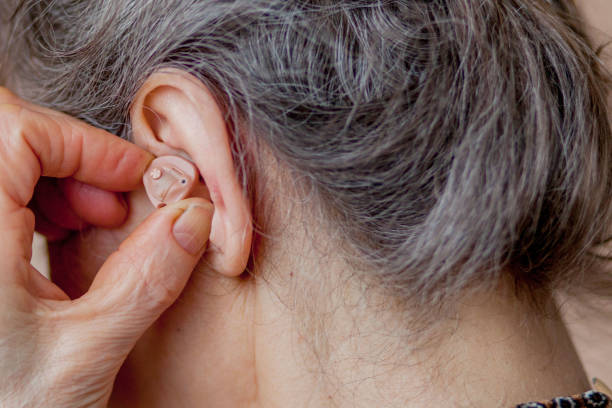 istock closeup senior woman inserting hearing aid in her ears 1154770157