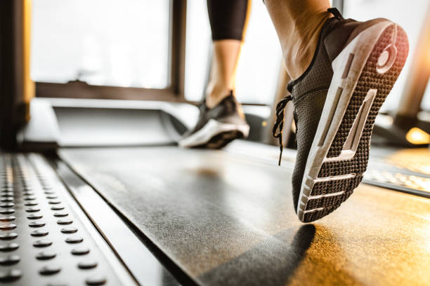 cerca de atleta irreconocible corriendo en una caminadora en un gimnasio. - máquinas de ejercicios fotografías e imágenes de stock