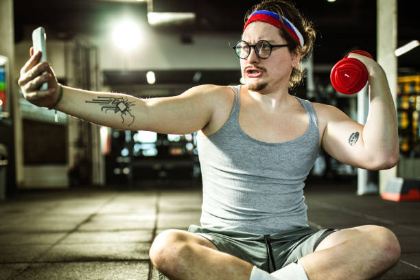 istock Funny nerdy athlete showing off while taking a selfie in a gym. 1154772214