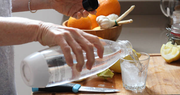 woman lemon water kitchen - transparent holding glass focus on foreground imagens e fotografias de stock
