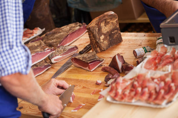 Traditional smoked speck sliced on site during the "Speckfest" celebration in Val di Funes, Dolomites. stock photo