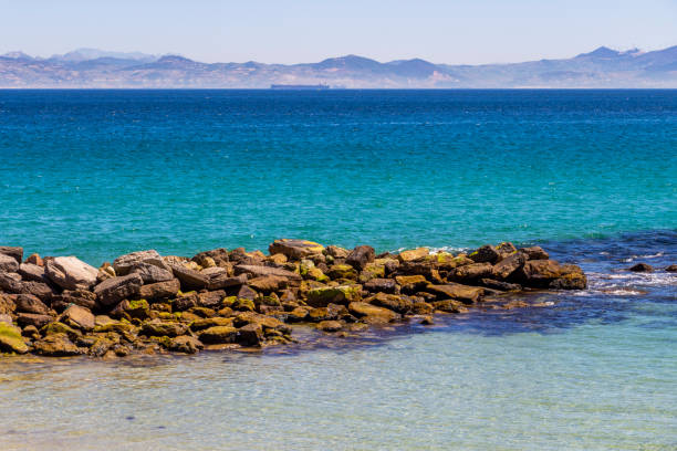 View from Tarifa near Playa Chica, Province of Cadiz, Andalusia Spain across the Straits of Gibraltar with stone breakwater in the foreground
