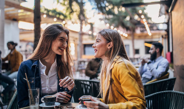 las mujeres bonitas bebiendo café en un jardín de café - coffee buzz fotografías e imágenes de stock