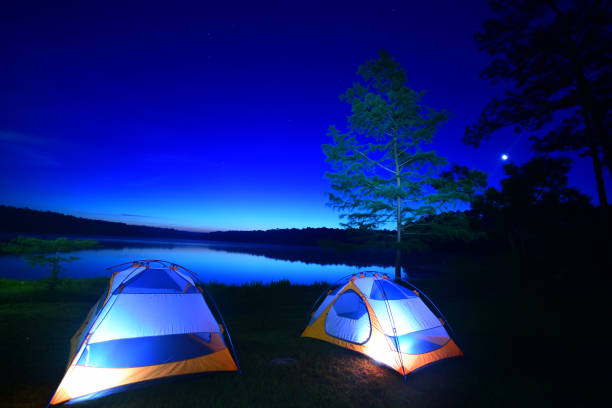 Lakeside tent camping with pre-dawn sky reflection