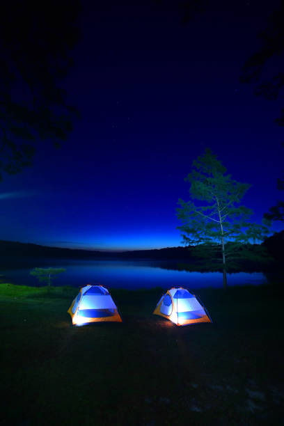 istock Lakeside tent camping on grassy bank with pre-dawn sky reflection 1154776466