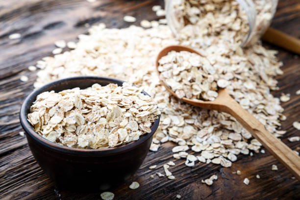 istock Spoon and bowl with raw oatmeal on the table. Top view, horizontal. 1154777931