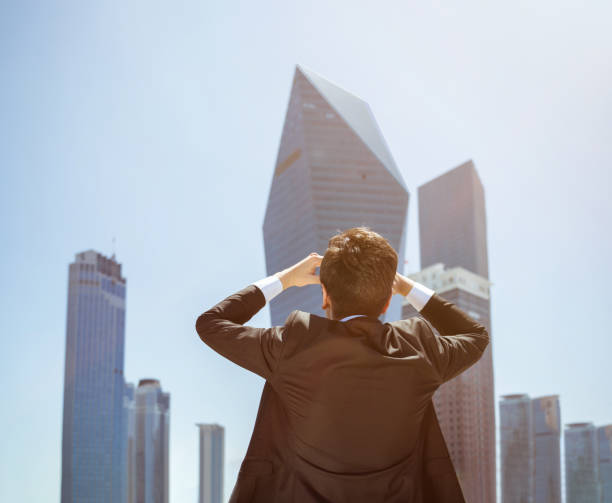 istock Businessman Looking up at skyscraper Back view 1154778594