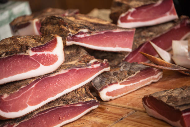 Traditional smoked speck sliced on site during the "Speckfest" celebration in Val di Funes, Dolomites. stock photo