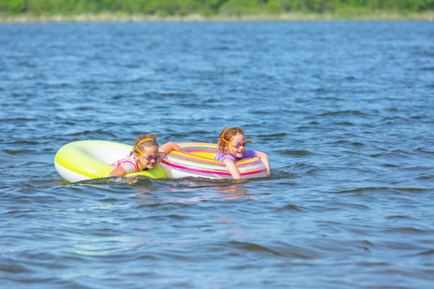 istock Two Girls Playing on Innertube Float Toys On Lake 1154779516