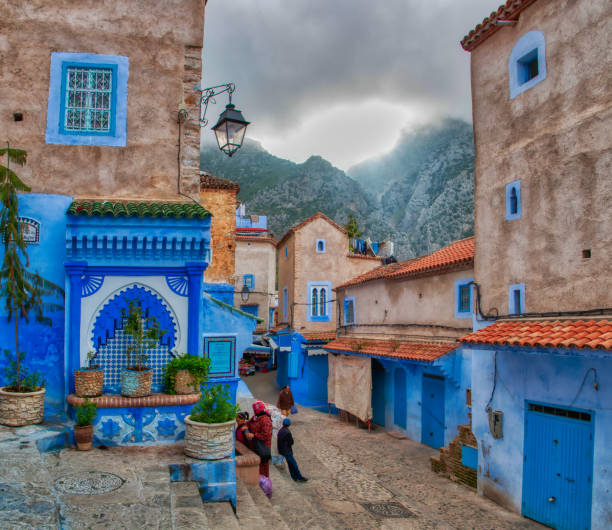 Chefchaouen, Morocco - May 4, 2019: Everyday life in a beautiful street of Chefchaouen with a dramatic sky in the background.