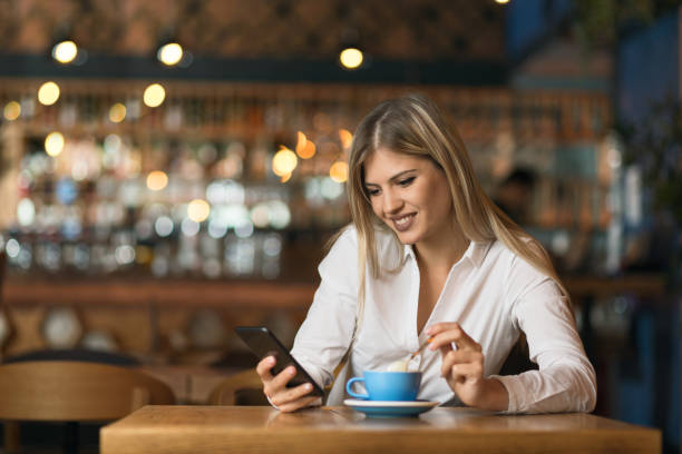 istock Happy young woman using cell phone during coffee time 1154781421