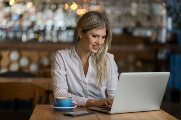 istock Young  woman using laptop and surfing the Internet in a cafe 1154782110