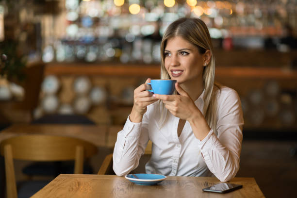 istock Young woman drinking coffee in a cafe and looking away 1154782121