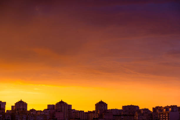 Modern city skyline. Dramatic orange sunset clouds over modern city rooftops.