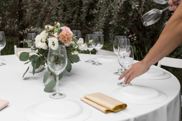 istock The waiter serves banquet table. Wedding table setting decorated with flowers and brass candlesticks with candles. 1154784182