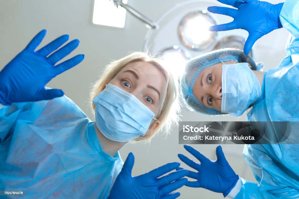 Crazy Scary And Funny Doctors Surgeons Dentists In Masks With Gloves And  Coats Scare And Tease On Camera A Nightmare Patient Portraits Of Doctors  Closeup Firstperson View Lamp Background Stock Photo -