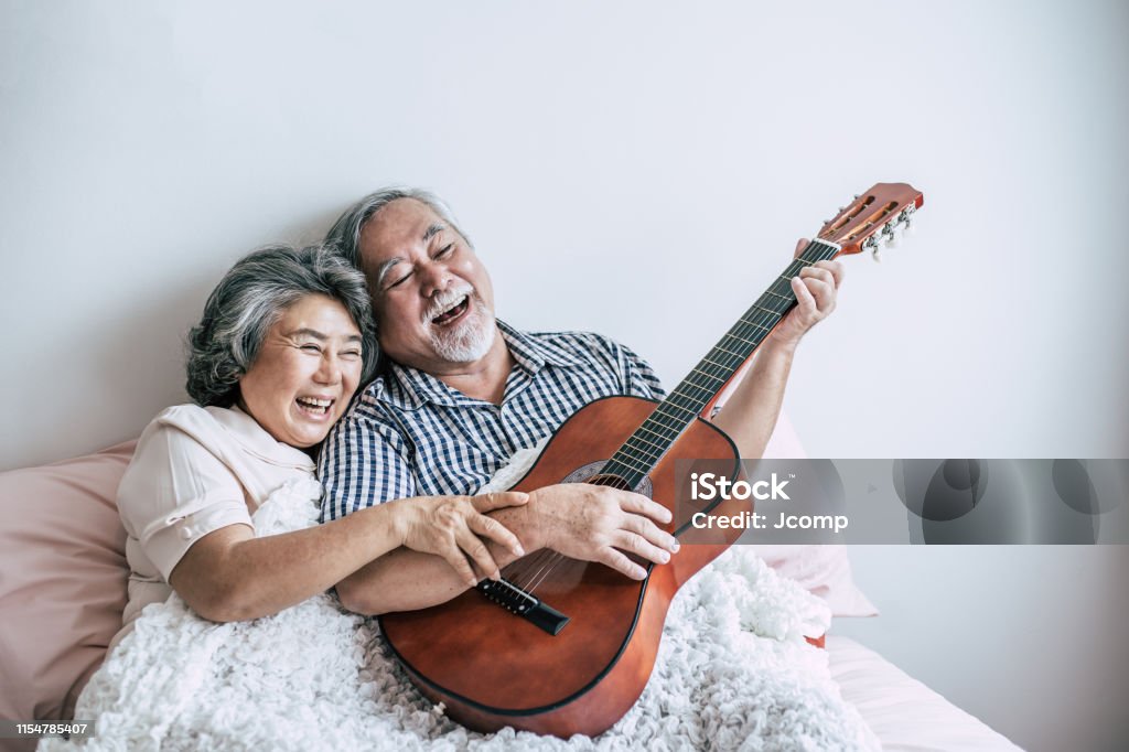 Senior couple  relax playing acoustic guitar in bed room Senior Adult Stock Photo