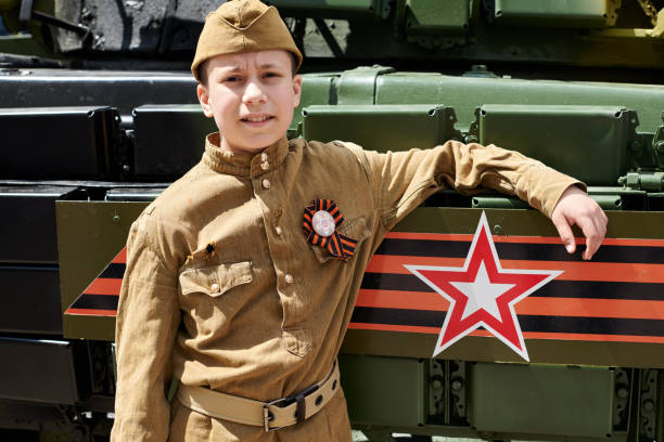 istock Boy dressed in Soviet military uniform during the second world war posing near army tank 1154785882
