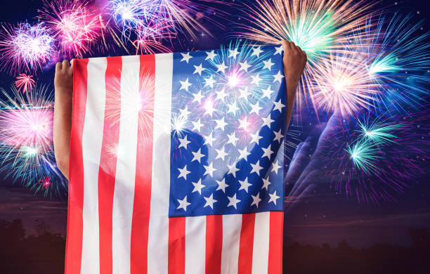 istock Man holding USA flag with fireworks 1154791587