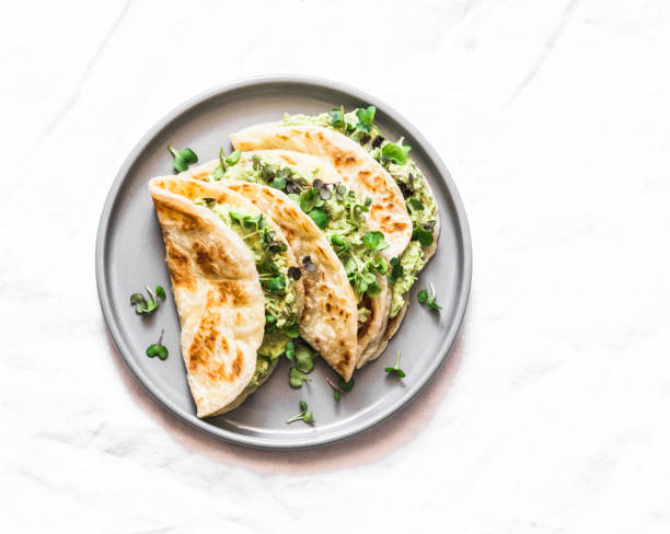 Avocado eggs greens salad paratha flatbread quesadilla on a light background, top view