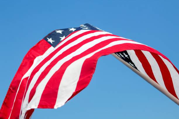 istock American Flag waving in the wind against blue sky 1154793221