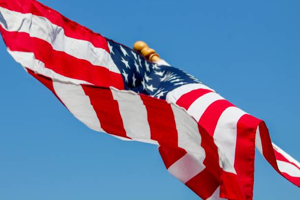 istock American Flag waving in the wind against blue sky 1154793270