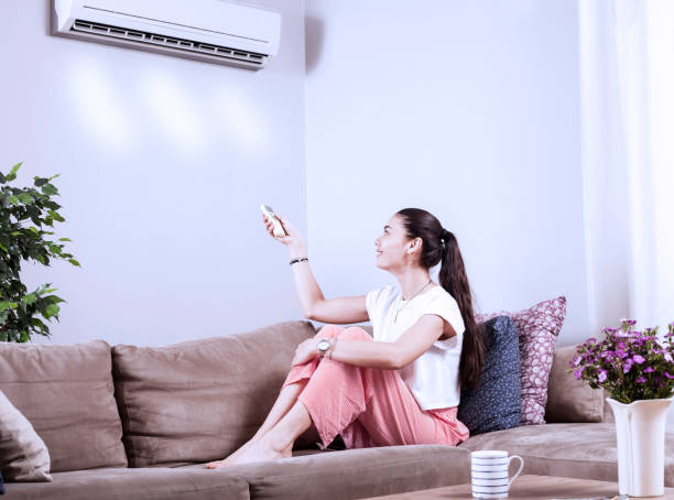 istock woman using remote control of airconditioner 1154797074