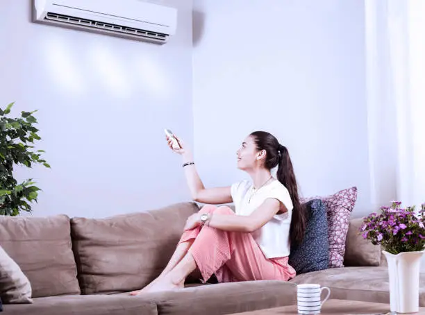 woman using remote control of airconditioner