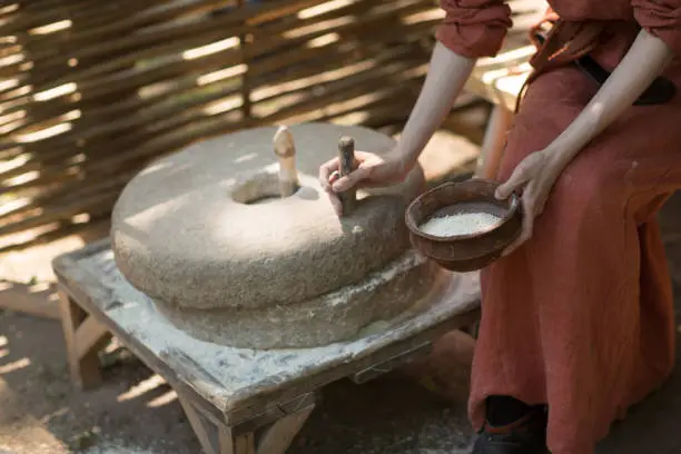 Photo of Woman grinds wheat and makes flour on millstone