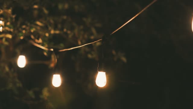 outdoor party string lights hanging on a line in backyard. dolly shot