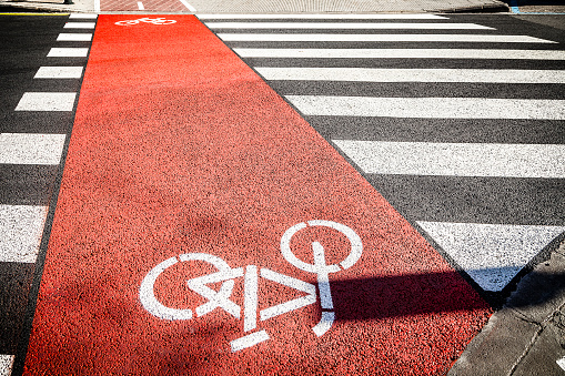 Red bicycle lane and white crosswalk painted on new asphalt in a sunny day. DSRL outdoors photo taken with Canon EOS 5D Mk II and Canon EF 24-105mm f/4L IS USM Wide Angle Zoom Lens