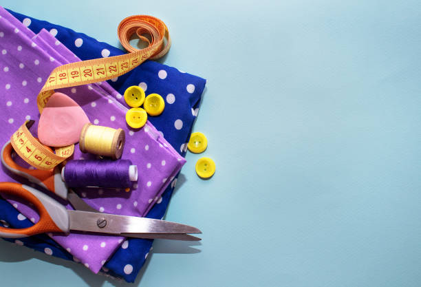 istock Sewing accessories and fabric on a blue background. Concept for needlework, stiching, embroidery. Sewing multicolored threads, needles, pins, fabric, buttons and sewing centimeter. top view, flatlay 1154803815
