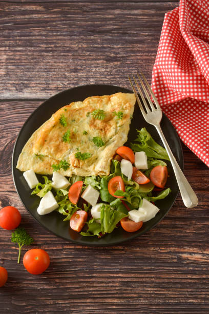 istock Egg omelette with cherry tomato, mozzarella and green. Wooden background. 1154804418