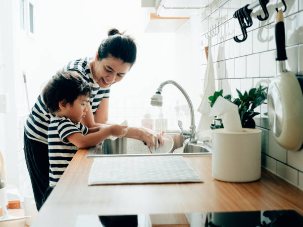 若い女性は自宅で彼女の息子と一緒に料理を掃除します。 - rubbing human hand togetherness women ストックフォトと画像