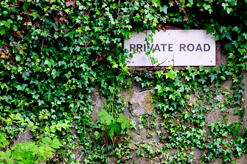 Private road sign on wall covered in ivy uk