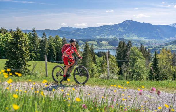 senior woman on mountain bike senior woman mountain biking on a e-mountain bike in early spring, in the Allgaeu Area, a part of the bavarian alps,Germany allgau stock pictures, royalty-free photos & images