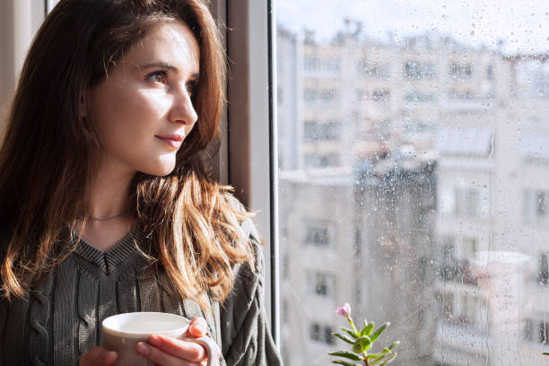 istock beautiful woman looking from window 1154810610
